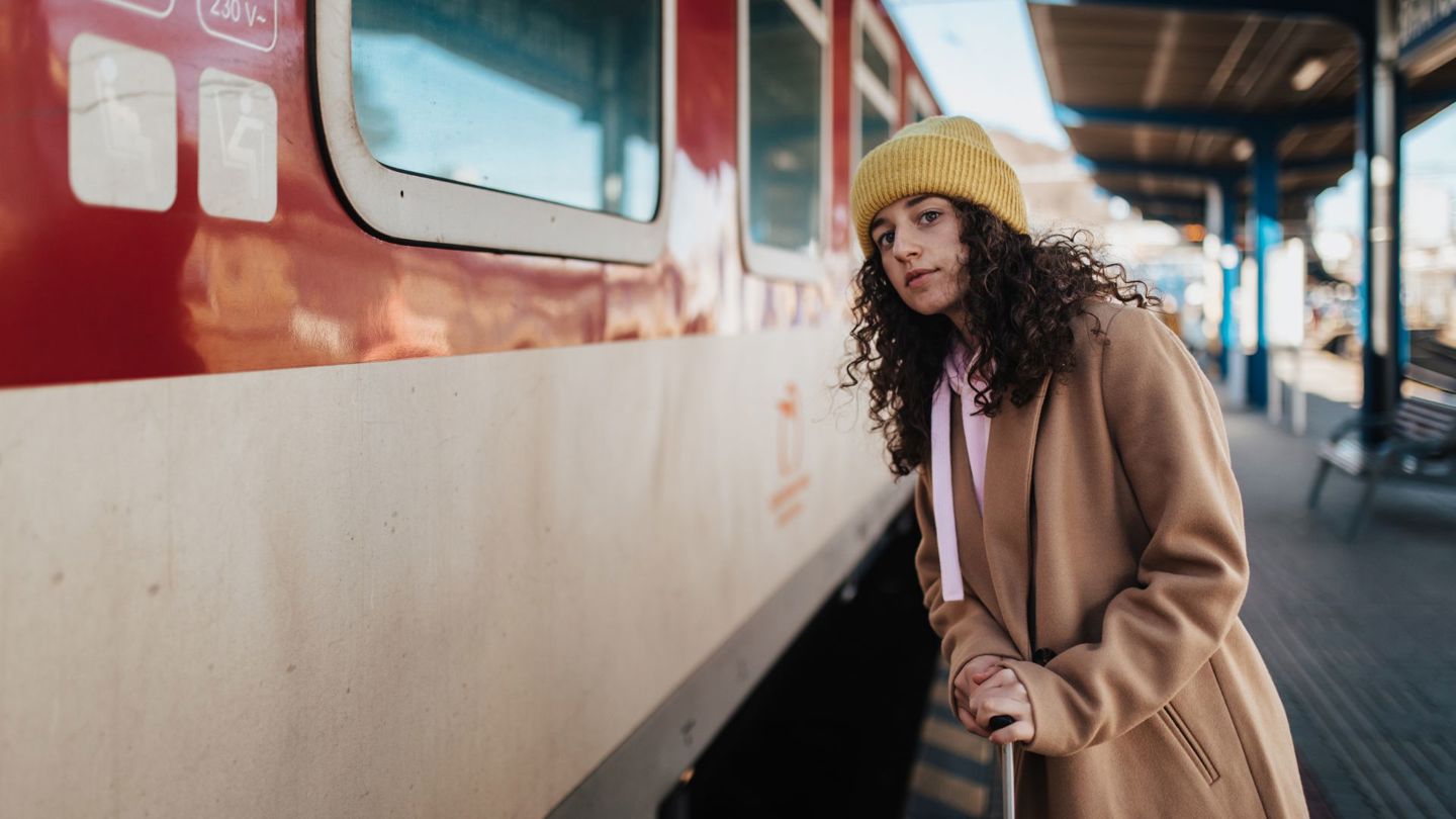 Bildet viser en kvinne som står på en togstasjon.